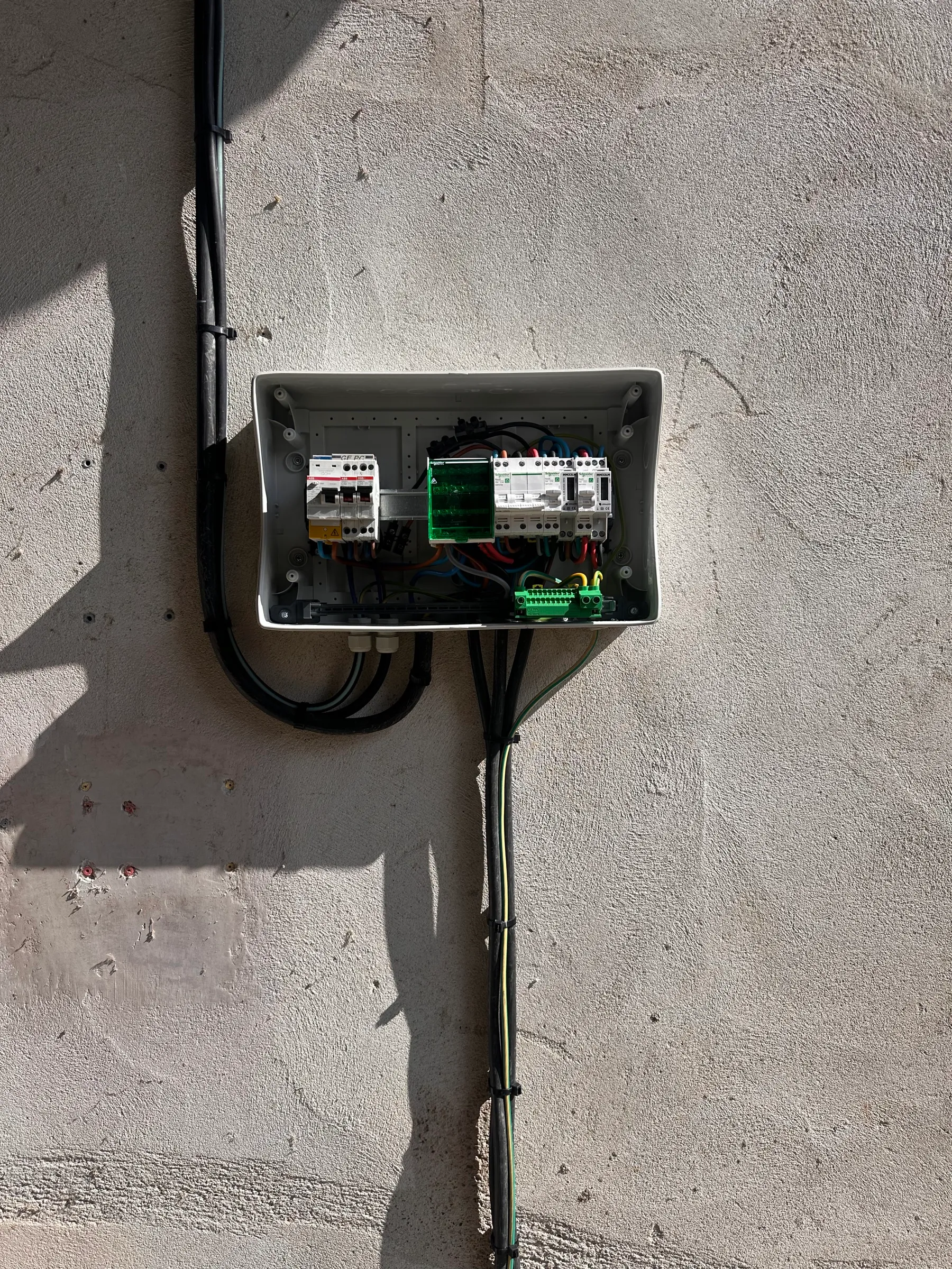 Installation électrique d'une maison neuve : coffret étanche posé en extérieur, protections et bornier de terre raccordés